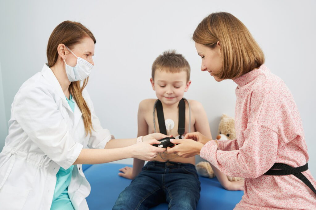 Doctor giving ECG holter monitor to woman in pediatric clinic