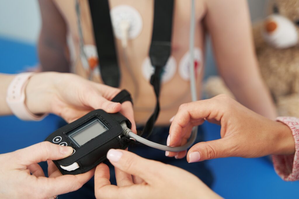 Doctor showing ECG holter monitor to patient in pediatric clinic