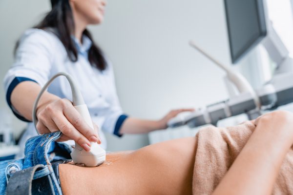 Close up of female doctor doing ultrasound probe on patient stomach in medical clinic